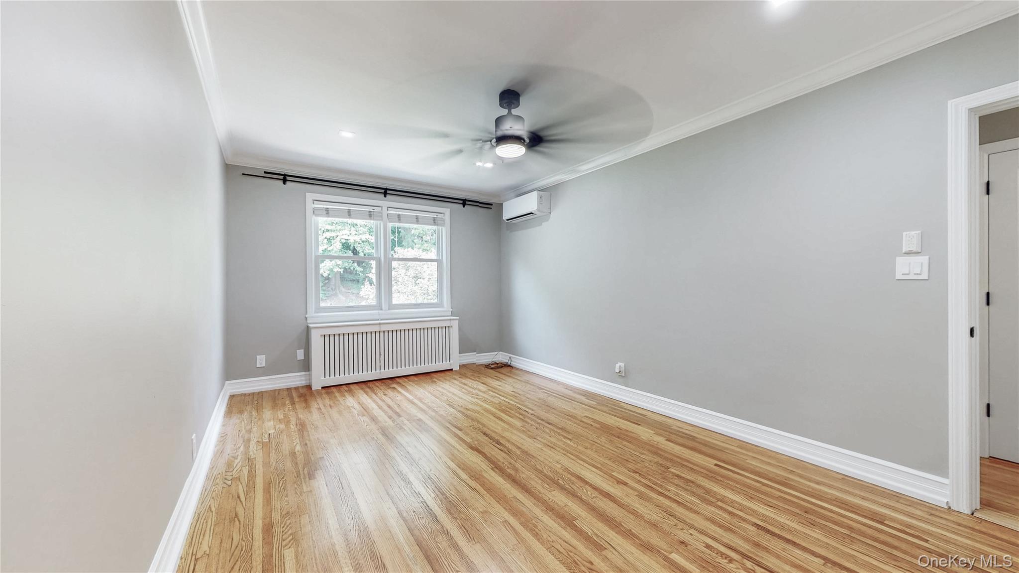 67-04 Selfridge Street, Unit 2 Queens, NY 11375 - Photo 13 of 21 an empty room with wooden floor ceiling fan and windows