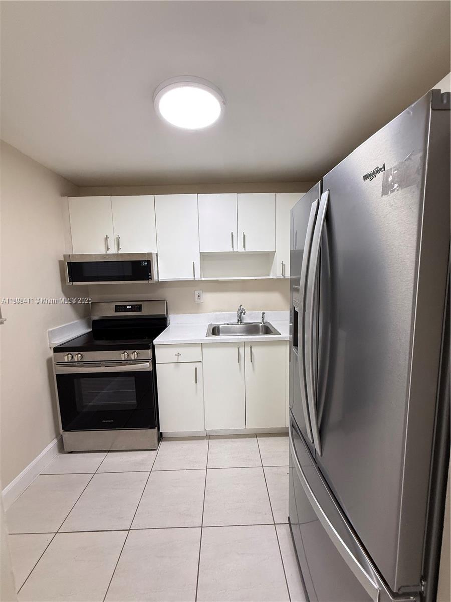 1725 West 60th Street, Unit 105 Hialeah, FL 33012 - Photo 4 of 19 a kitchen with a refrigerator sink and cabinets