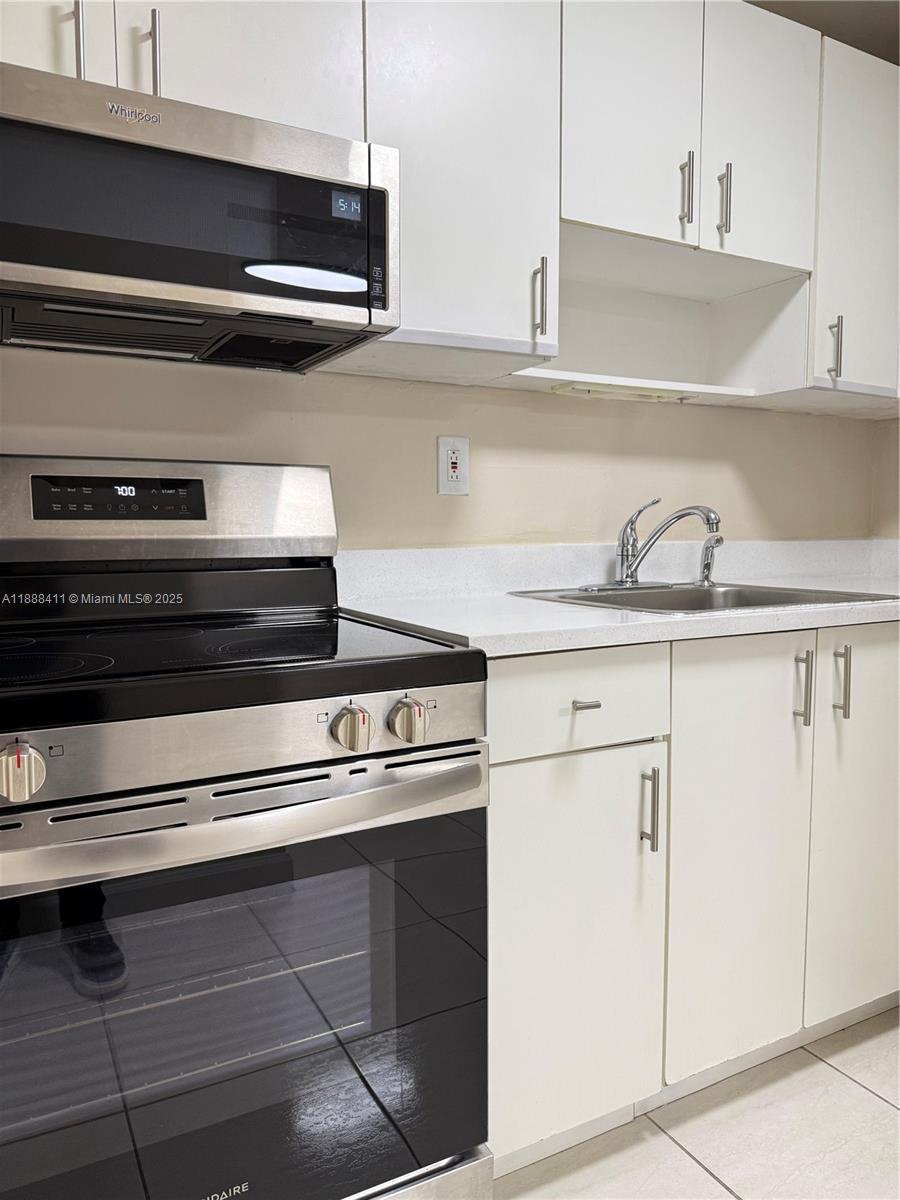 1725 West 60th Street, Unit 105 Hialeah, FL 33012 - Photo 6 of 19 a kitchen with granite countertop cabinets stainless steel appliances and sink