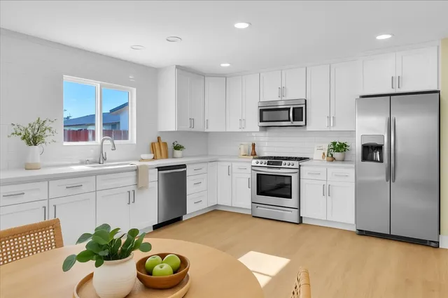 a kitchen with stainless steel appliances a stove a sink a microwave and a refrigerator