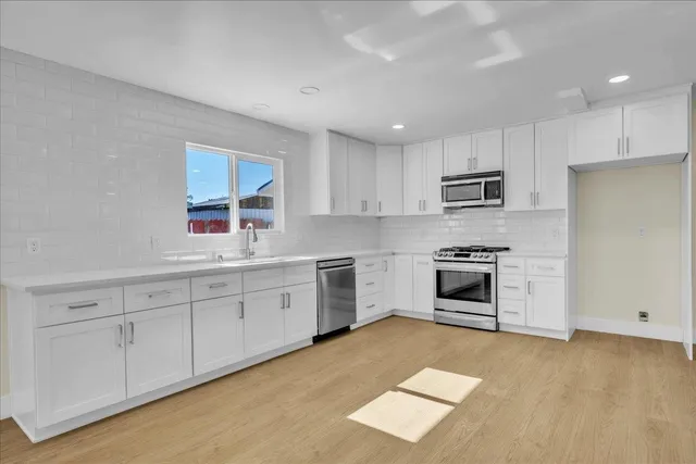 a kitchen with white cabinets and stainless steel appliances