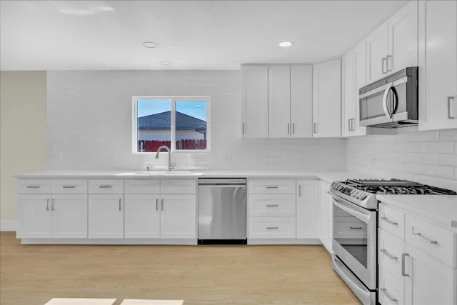 a kitchen with stainless steel appliances granite countertop a stove a sink and a microwave