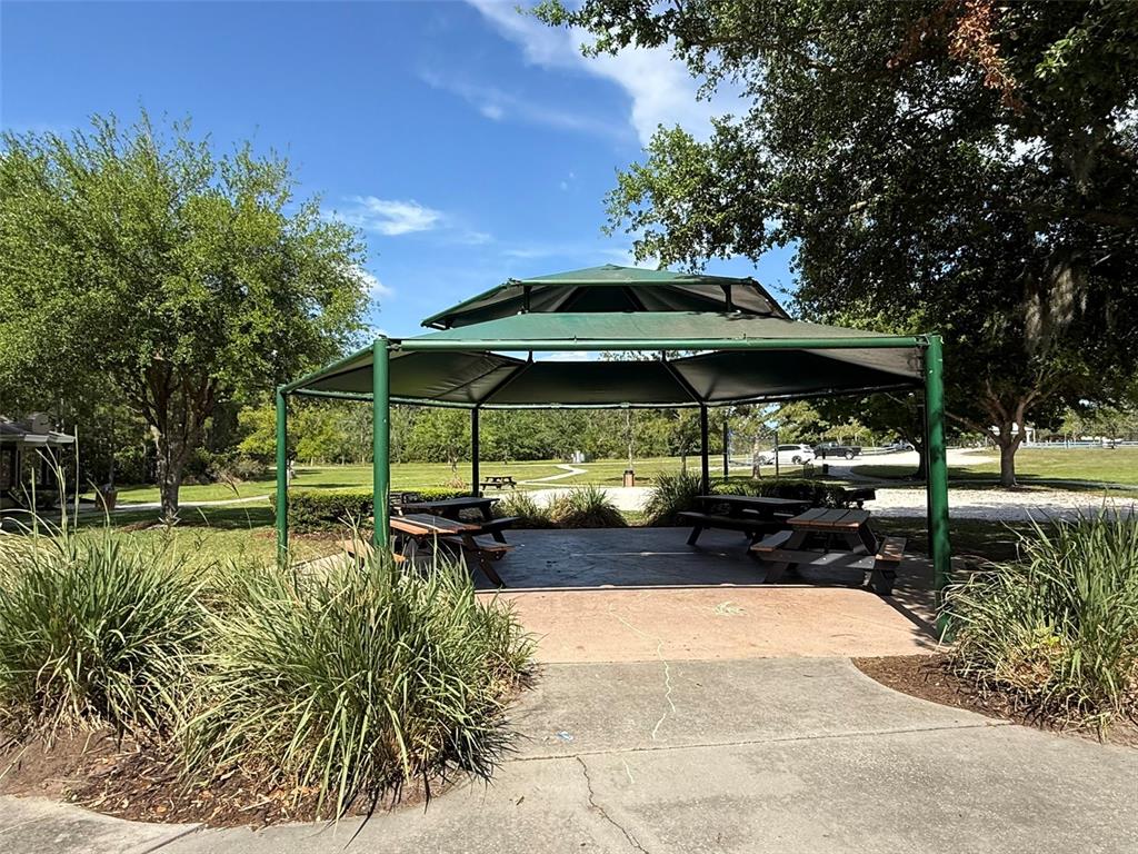 3468 Middlebrook Place St. Cloud, FL 34773 - Photo 25 of 32 a view of a patio with table and chairs under an umbrella with large trees