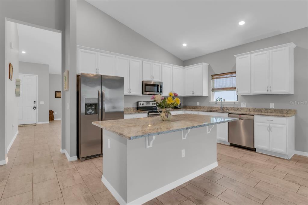 3468 Middlebrook Place St. Cloud, FL 34773 - Photo 5 of 32 a kitchen with stainless steel appliances granite countertop a refrigerator a stove a sink a microwave and white cabinets
