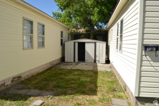 230 North 2nd Street Tooele, UT 84074 - Photo 18 of 18 Compact side yard featuring a metal storage shed on a concrete pad, flanked by two buildings with horizontal siding