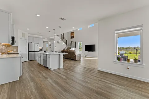 a kitchen with stainless steel appliances kitchen island wooden floors stove and white cabinets