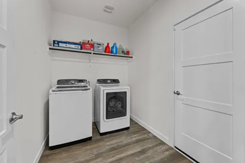 a utility room with wooden floor washer and dryer
