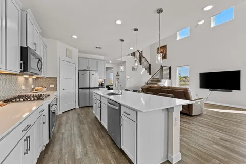 a large kitchen with stainless steel appliances kitchen island granite countertop a stove a sink a refrigerator and a wooden floors