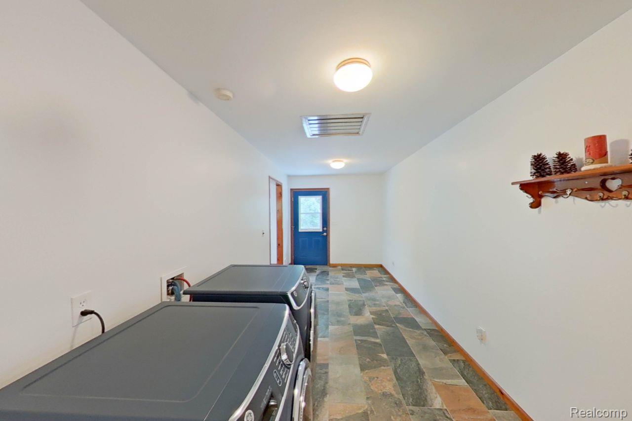 10201 Washburn Road Goodrich, MI 48438 - Photo 39 of 85 Spacious utility room featuring multi-toned slate-style flooring, a wall-mounted ceiling light fixture, a ceiling vent, and a solid blue exterior door