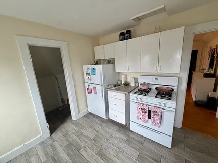 a utility room with refrigerator a stove and wooden floor
