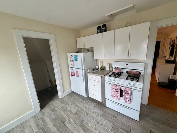 a utility room with refrigerator a stove and wooden floor
