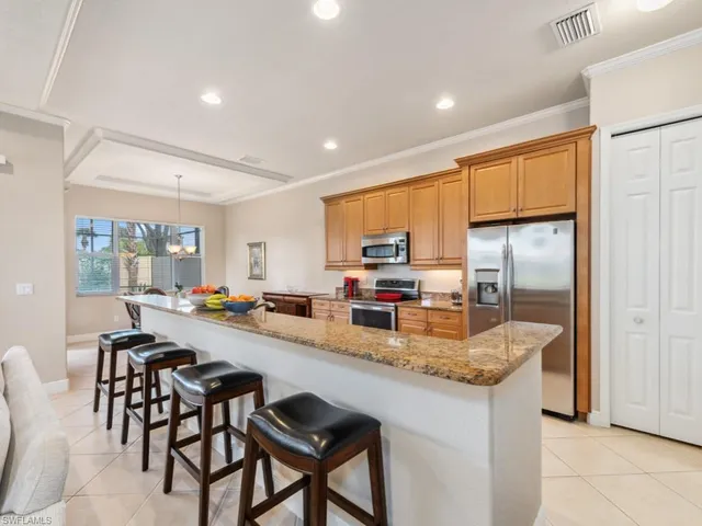 a kitchen with sink a refrigerator and chairs