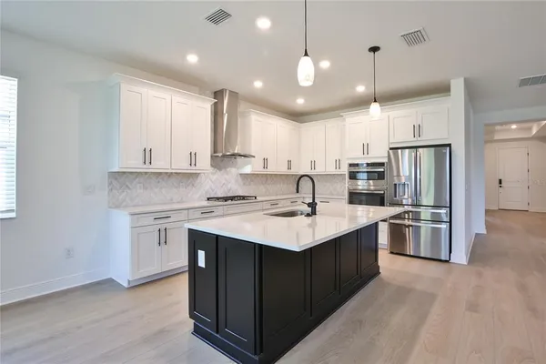 a kitchen with stainless steel appliances granite countertop a sink a stove a refrigerator and island with wooden floor