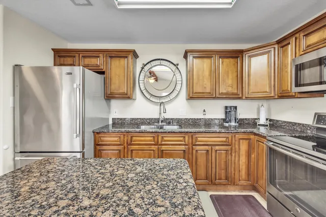 a kitchen with kitchen island granite countertop a stove a sink and a refrigerator