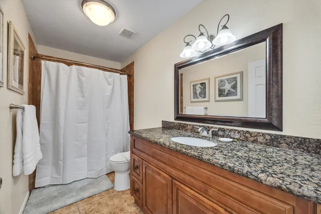 a bathroom with a granite countertop sink a toilet and a shower