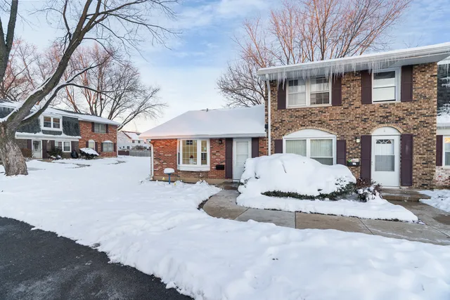 a front view of a house with a yard covered in snow