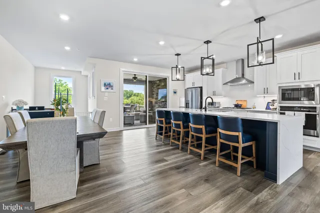 a kitchen with stainless steel appliances kitchen island granite countertop a wooden table chairs and white cabinets