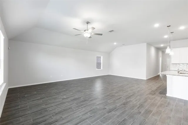 an empty room with wooden floor chandelier fan and windows