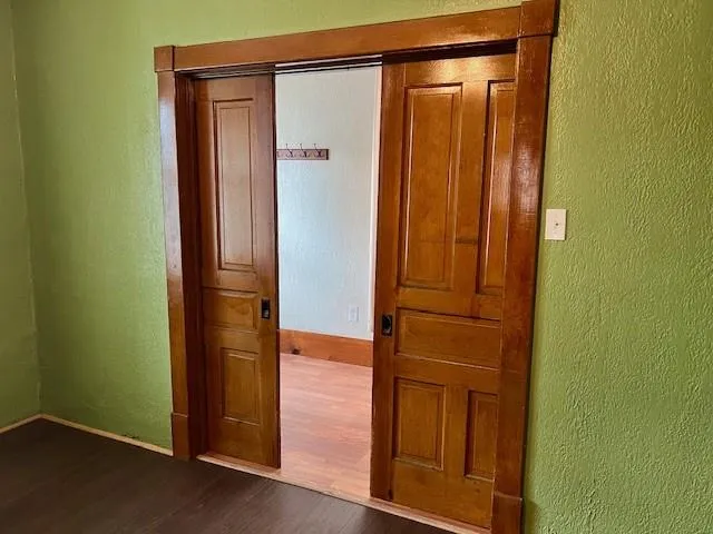 a view of an empty room with wooden floor and a window