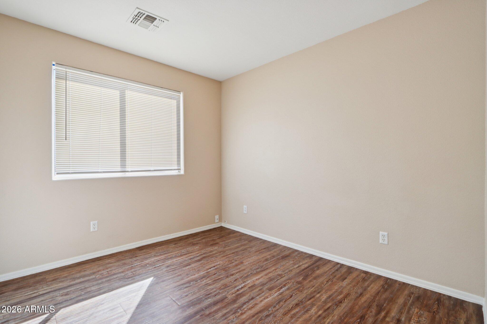 3326 West Shumway Farm Road Phoenix, AZ 85041 - Photo 17 of 30 an empty room with wooden floor and windows