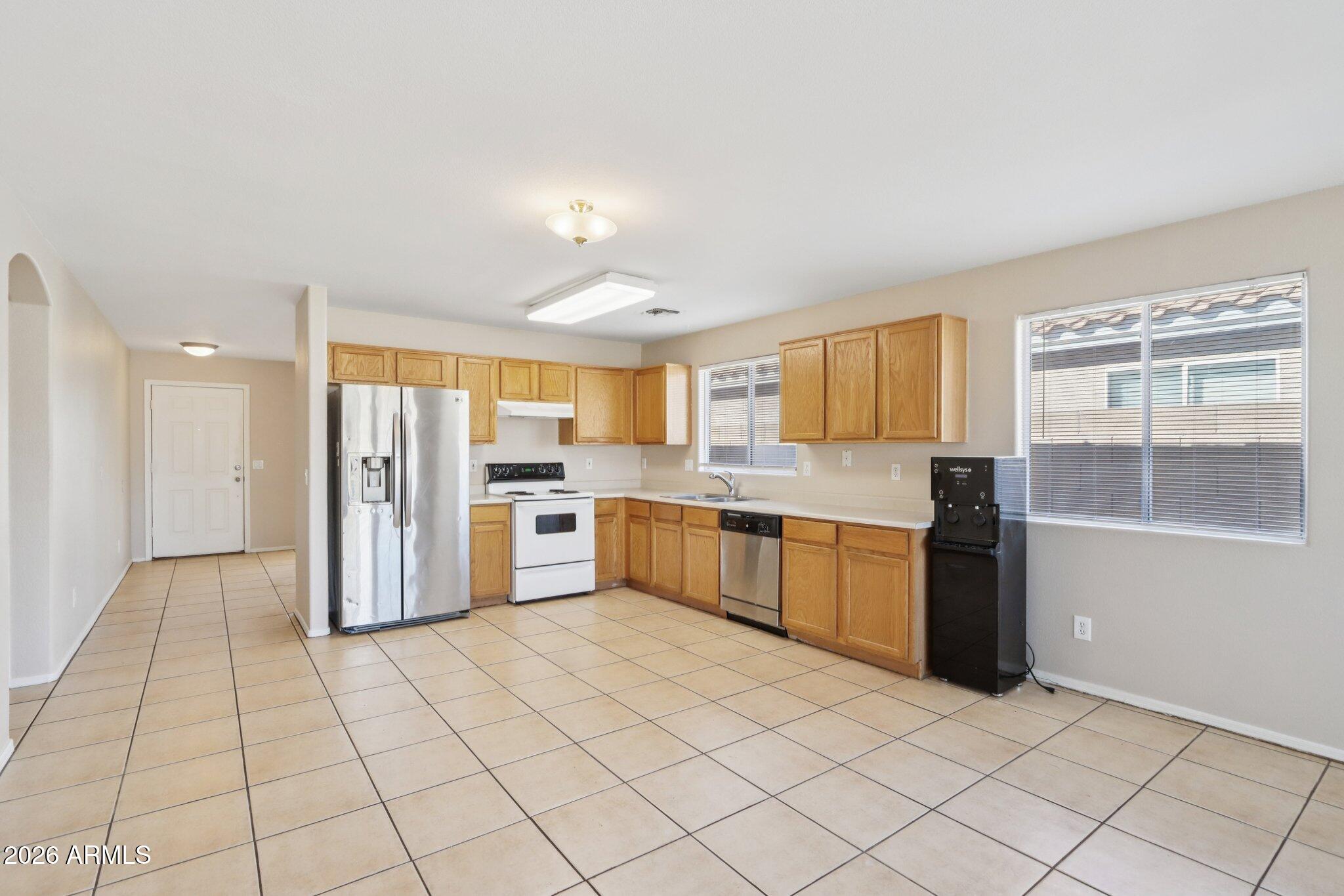 3326 West Shumway Farm Road Phoenix, AZ 85041 - Photo 10 of 30 a large kitchen with a stove a sink dishwasher a refrigerator and white cabinets with wooden floor