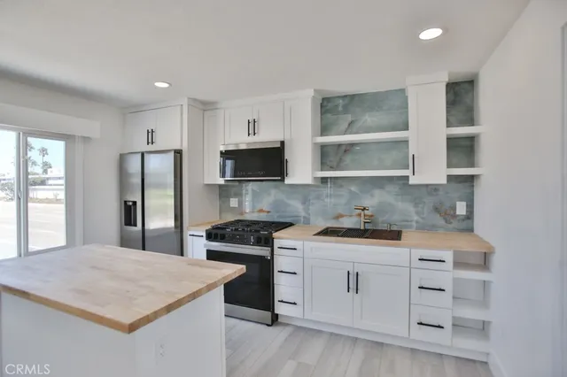 a kitchen with white cabinets stainless steel appliances and window