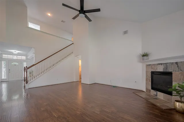 a view of an empty room with wooden floor fireplace and a window