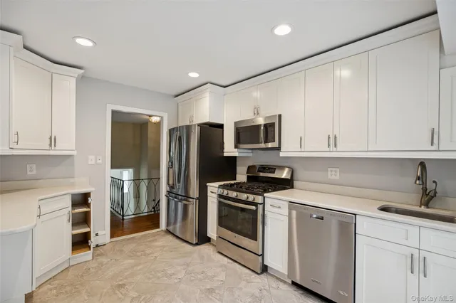 a kitchen with stainless steel appliances white cabinets and a stove top oven