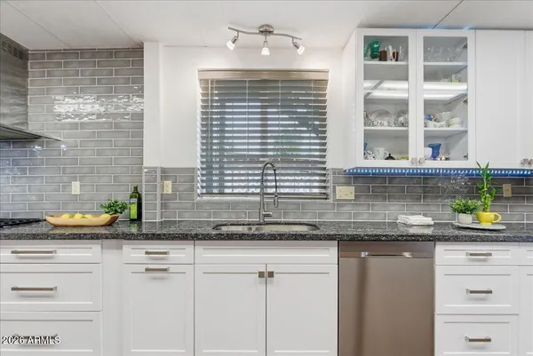 a kitchen with stainless steel appliances granite countertop a stove a sink dishwasher and white cabinets with wooden floor