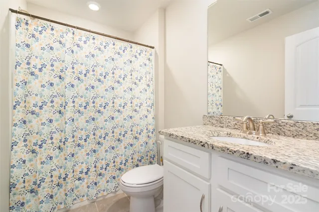 a bathroom with a granite countertop sink a toilet and a mirror
