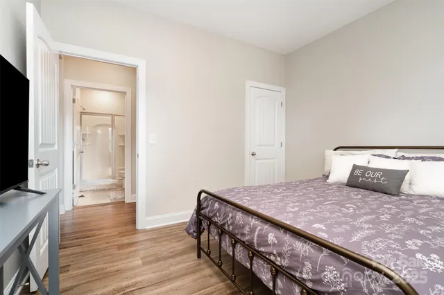 a bedroom with a bed a flat screen tv and a chandelier