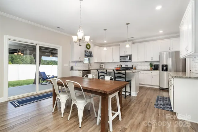 a view of a dining room and livingroom with furniture wooden floor a chandelier