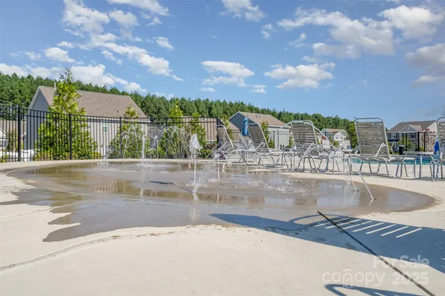a view of a patio with dining table and chairs under an umbrella with large trees