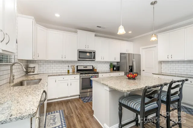 a kitchen with a refrigerator a stove a sink dishwasher a oven with a dining table and chairs