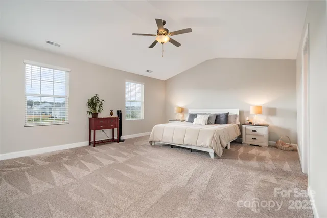 a spacious bedroom that has a bed and a chandelier