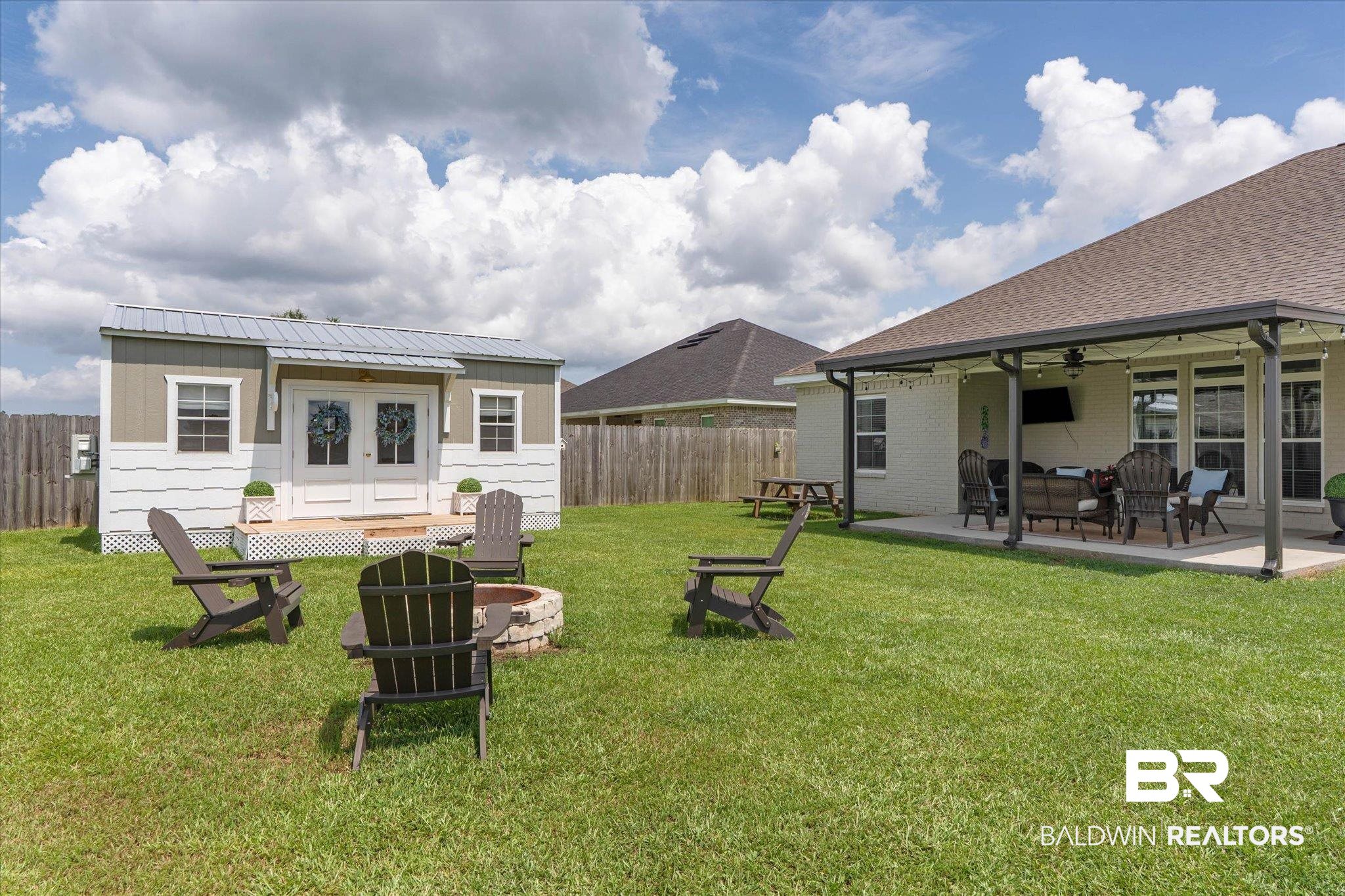 9074 Moses Way Theodore, AL 36582 - Photo 45 of 52 Expansive backyard featuring a detached accessory building with a metal roof and double pane windows, a covered patio with recessed lighting, a built-in fire pit, and a full privacy fence