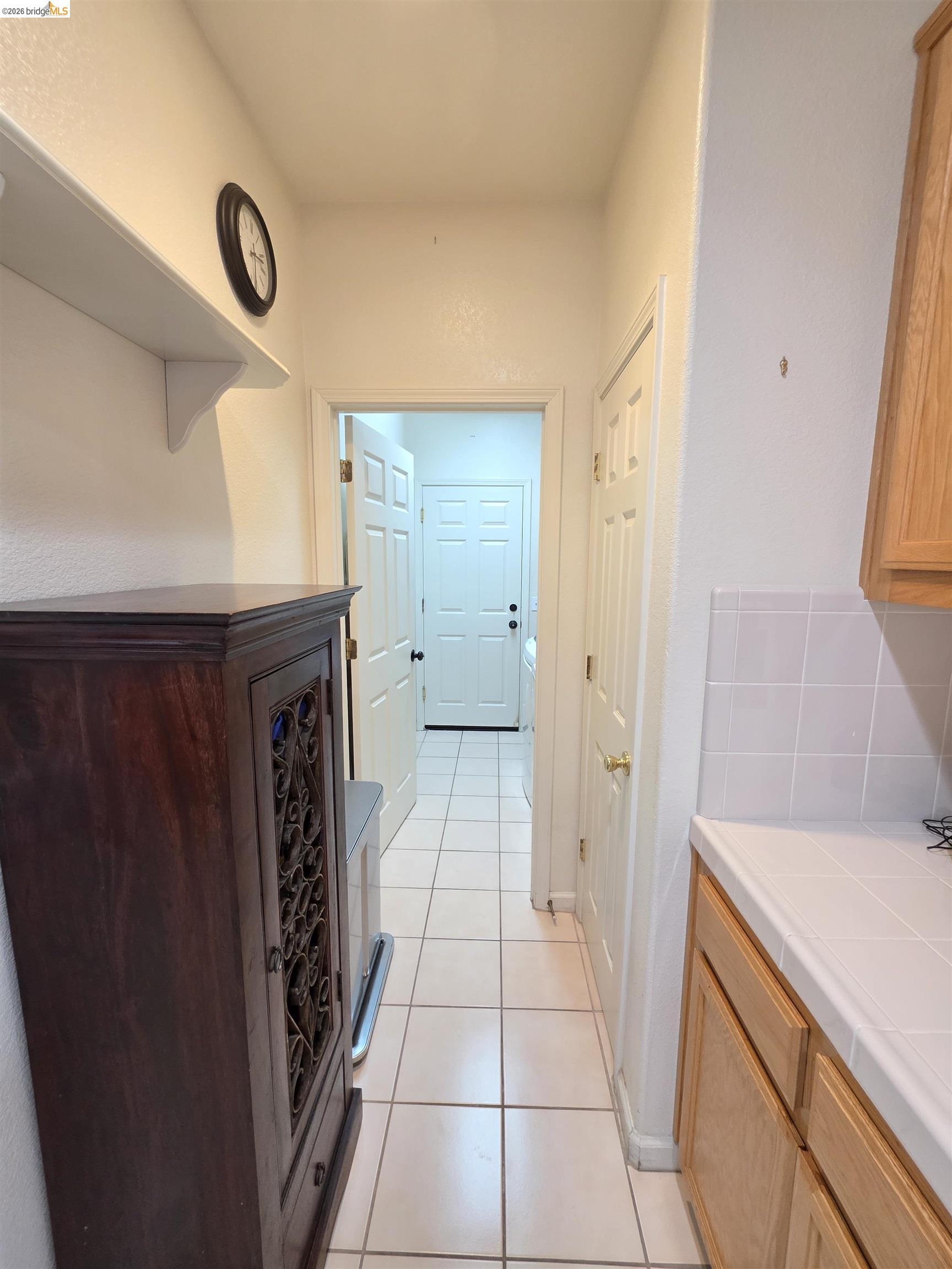 2607 Glow Road Riverbank, CA 95367 - Photo 24 of 42 White tile flooring, white walls, light wood cabinetry, and white tile backsplash