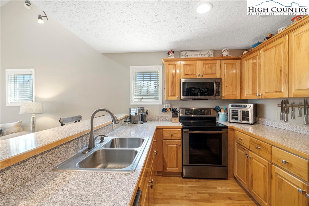 446 Peaceful Haven Drive, Unit 832 Boone, NC 28607 - Photo 9 of 38 a kitchen with granite countertop a stove a sink and a microwave