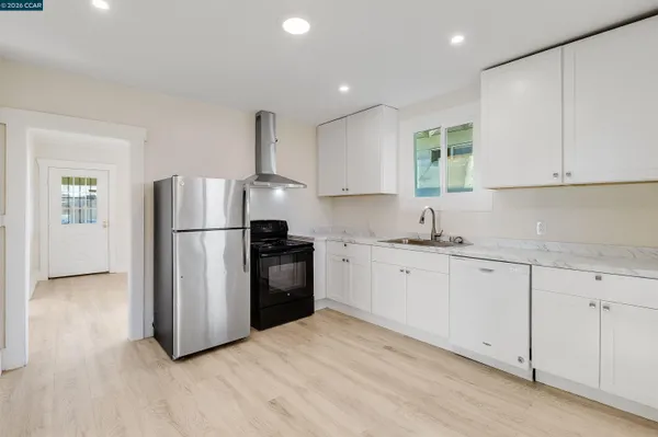 a kitchen with granite countertop a refrigerator sink and white cabinets