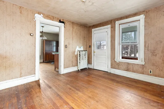 a view of an empty room with wooden floor and a window