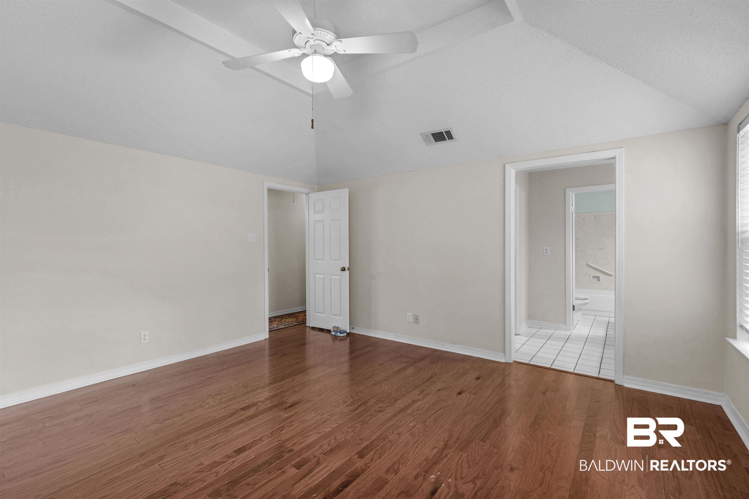 7225 Smithfield Road East Mobile, AL 36695 - Photo 16 of 27 Unfurnished room with a ceiling fan, wood finished floors, visible vents, baseboards, and vaulted ceiling