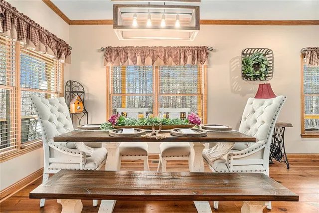 a large kitchen with stainless steel appliances kitchen island granite countertop a large stove a refrigerator a sink a dining table and chairs with wooden floor