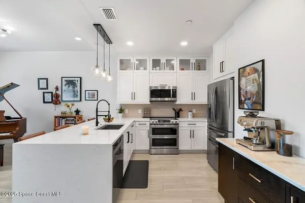 a kitchen with stainless steel appliances a sink stove refrigerator and cabinets