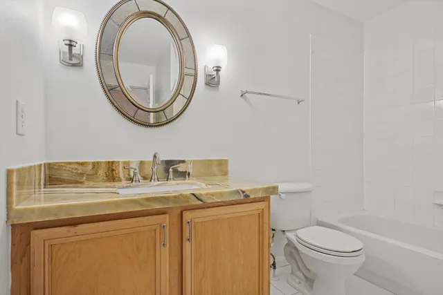a bathroom with a granite countertop toilet sink and mirror