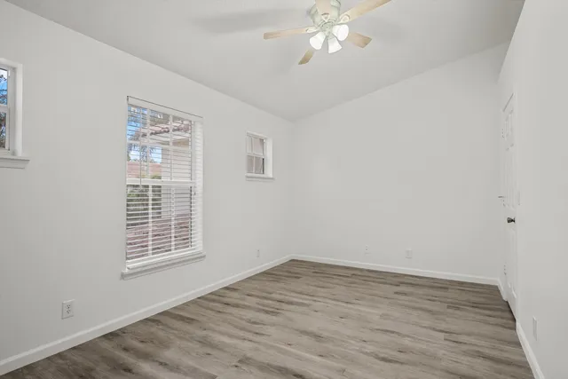a view of an empty room with wooden floor and a window