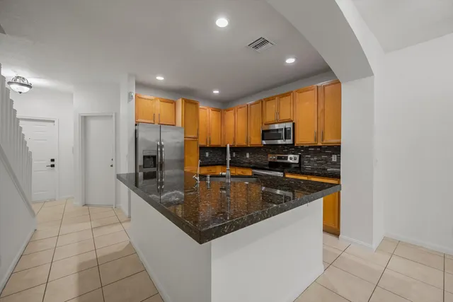 a kitchen with stainless steel appliances granite countertop a sink and a refrigerator