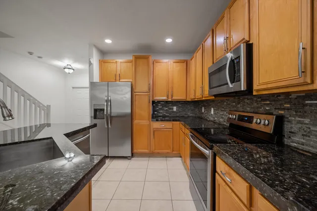 a kitchen with stainless steel appliances granite countertop a stove a sink and a microwave