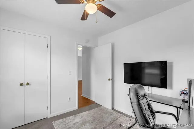 a living room with a flat screen tv and a ceiling fan