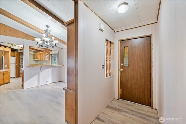 a view of a hallway with wooden floor and a kitchen