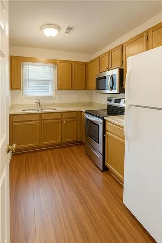 a kitchen with stainless steel appliances granite countertop a refrigerator a stove and a wooden floors